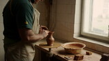 Ceramist making clay product in pottery. Senior man sculpting jar in workshop