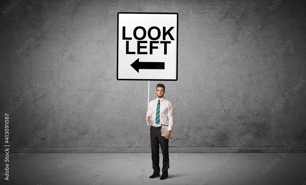 business person holding a traffic sign with LOOK LEFT inscription, new idea concept business person holding a traffic sign with LOOK LEFT inscription, new idea concept