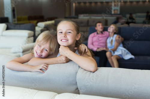 Portrait of sisters which are happy of the purchase of a new sofa in the store.