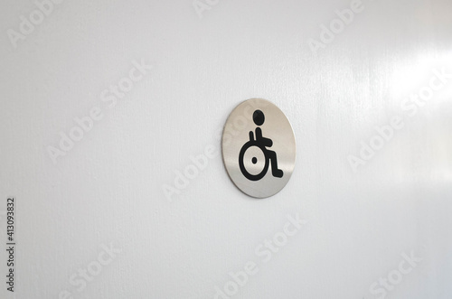 The disabled sign or wheelchair user and handicap on a white door or wall. Concept of accessible public facilities. Copy space for text.