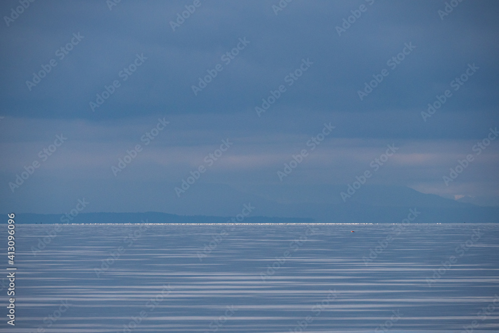 Obraz premium overcast day on the river with mountains over the horizon under heavy clouds