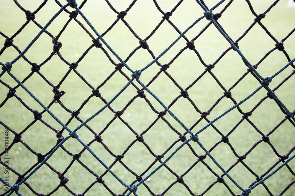 Selective focus at mesh fence with green grass field Selective focus at mesh fence with green grass field