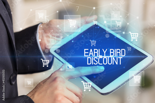 Young person makes a purchase through online shopping application with EARLY BIRD DISCOUNT inscription