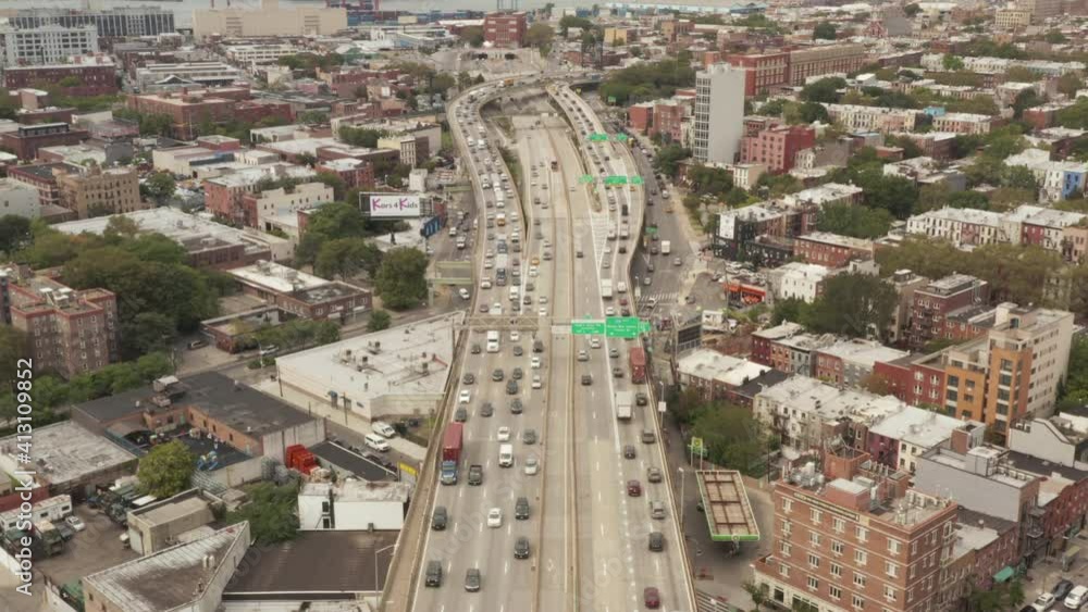 Aerial view flying backwards following multi lane city traffic across the bridge in industrial port area of New York City Aerial view flying backwards following multi lane city traffic across the bridge in industrial port area of New York City