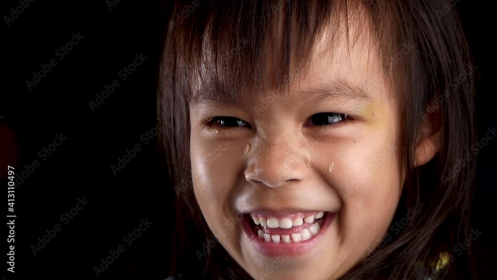 Close-up face portrait of cute little child girl looking at the camera and smiling with tears in studio at home. Concept of a happy childhood. Close-up face portrait of cute little child girl looking at the camera and smiling with tears in studio at home. Concept of a happy childhood.