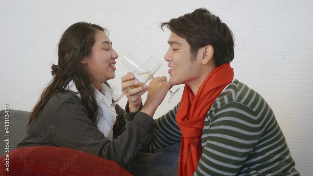 Happy Asian beautiful young family couple husband and wife on sofa in home living room, man and woman sit sofa in love clink glasses with champagne enjoy and drink winter holidays together Happy Asian beautiful young family couple husband and wife on sofa in home living room, man and woman sit sofa in love clink glasses with champagne enjoy and drink winter holidays together