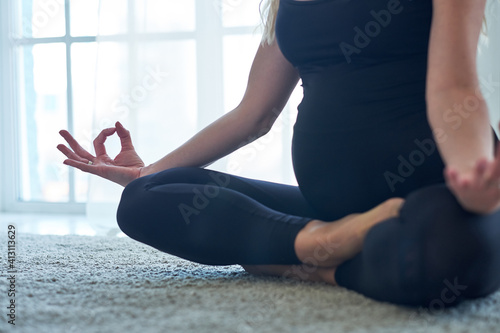 Yoga. Pregnant woman practicing yoga meditation in home. Health lifestyle concept and baby care