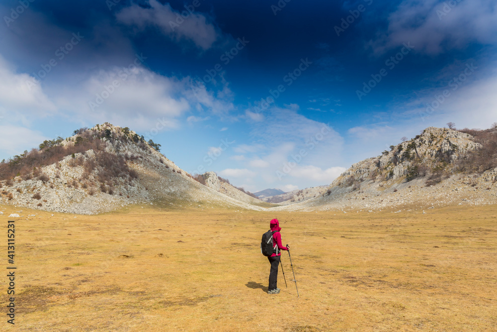 Beautiful scenery in the mountains with sharp limestome rocks, hiking path and April sky and showers, with cumulus clouds