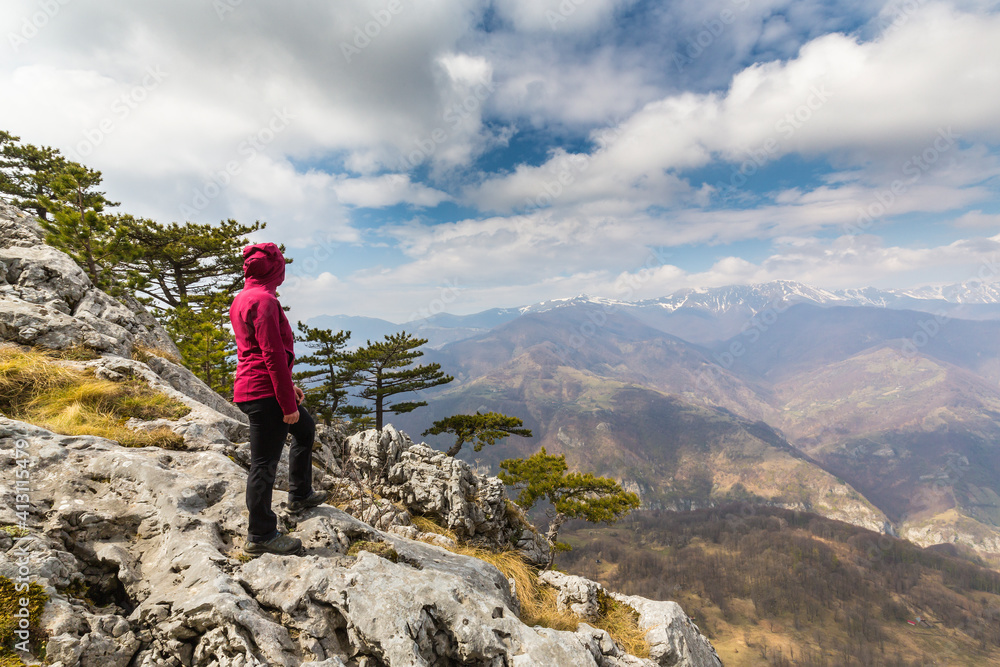 Fototapeta premium Beautiful scenery in the mountains with sharp limestome rocks, hiking path and April sky and showers, with cumulus clouds
