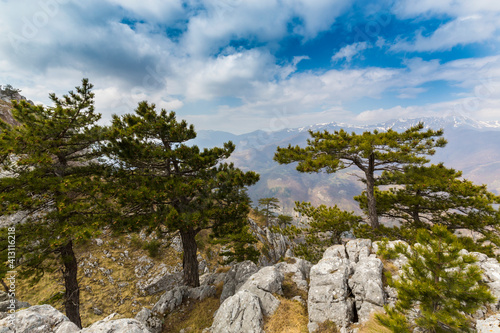 Beautiful scenery in the mountains with sharp limestome rocks, hiking path and April sky and showers, with cumulus clouds