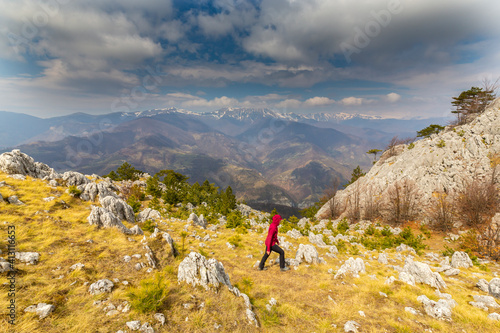 Beautiful scenery in the mountains with sharp limestome rocks, hiking path and April sky and showers, with cumulus clouds © Calin Tatu