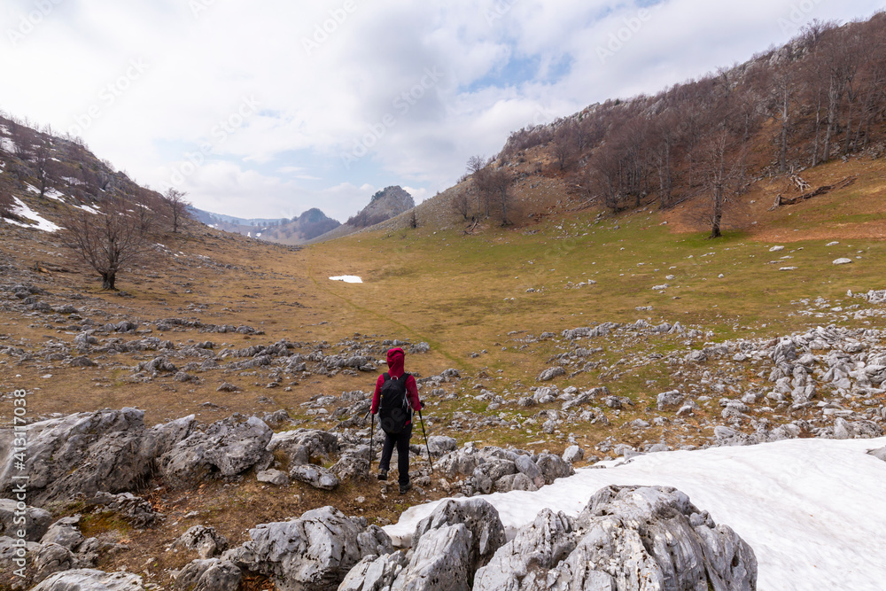 Beautiful scenery in the mountains with sharp limestome rocks, hiking path and April sky and showers, with cumulus clouds