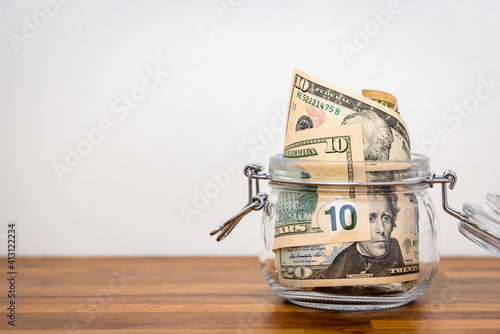 US Dollar cash banknote in glass jar put on wooden table with white background. Money saving concept. photo