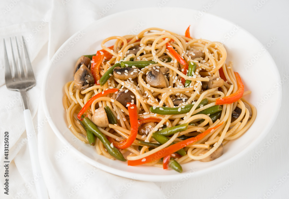 Noodles with vegetables (string beans, bell peppers, sesame seeds) and mushrooms in soy sauce, traditional Asian food