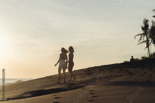 on the sand leaving behind the tracks goes into the distance the couple holding hands towards the sunset. High quality photo