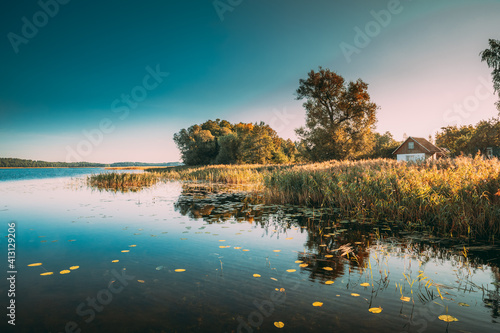 Summer Nature. Lake Or River In Beautiful Summer Sunny Day. Grass Growing On Coast. Sunny Day, Landscape With Lake And Old Small House On River Coast