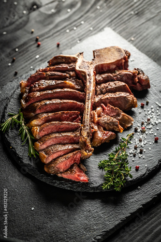 Barbecue dry aged Wagy porterhouse or T-bone beef steak sliced with large fillet piece with herbs and salt. banner, catering menu recipe place for text, top view photo