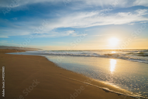 Sunset on the beach. Beautiful tranquil scene of empty sand beach, turquoise colored water, and cloudy sky
