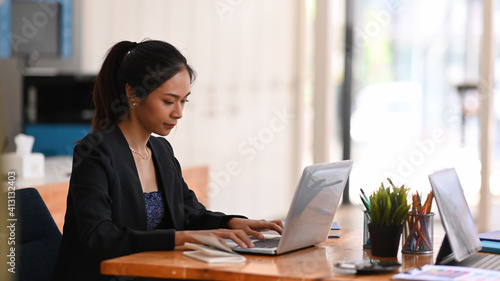 Young asian businesswoman working on her project with laptop computer while sitting a office desk.
