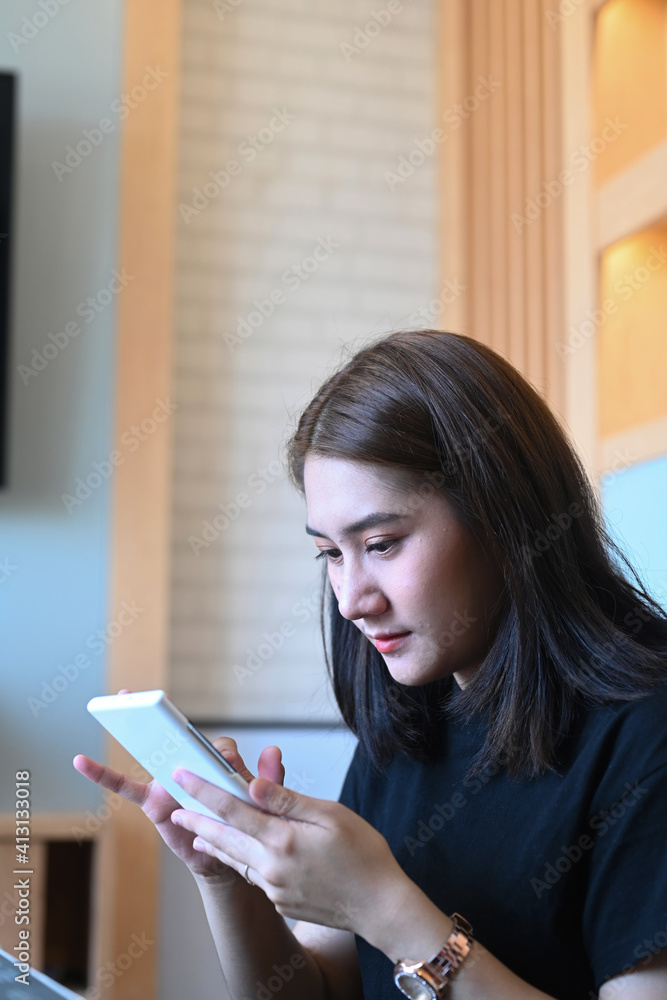 Portrait of smiling young female sitting in modern offie and using mobile phone. Portrait of smiling young female sitting in modern offie and using mobile phone.