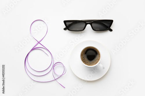 Figure 8 made of violet ribbon, cup of coffee and sunglasses on light background. International Women's Day celebration