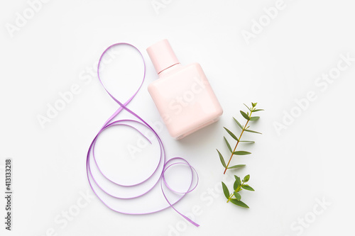 Figure 8 made of violet ribbon and perfume bottle on light background. International Women's Day celebration