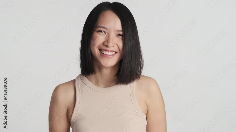 Beautiful smiling Asian girl agreeing on camera looking happy over white background. Young cheerful woman in studio Beautiful smiling Asian girl agreeing on camera looking happy over white background. Young cheerful woman in studio