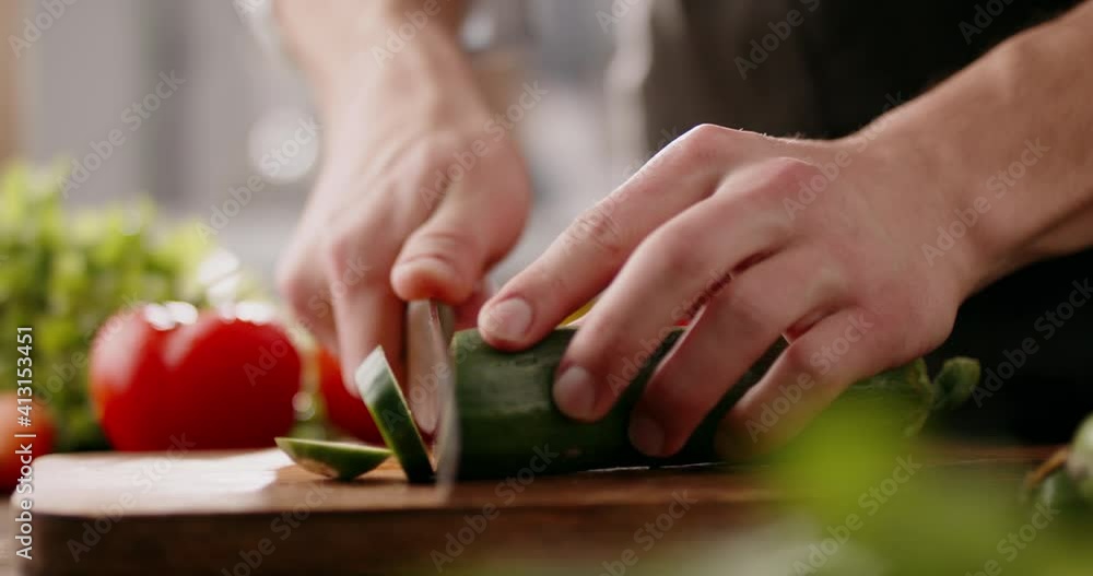 Chef cutting a fresh cucumber with knife on wooden board. Chef preparing vegetarian meal in the kitchen, 4k footage Chef cutting a fresh cucumber with knife on wooden board. Chef preparing vegetarian meal in the kitchen, 4k footage