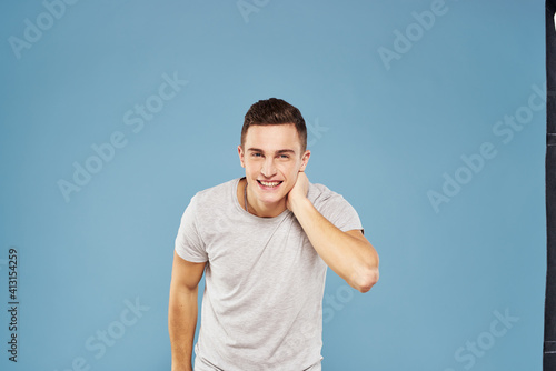 cheerful man in a white t-shirt gesturing with his hands emotions blue background