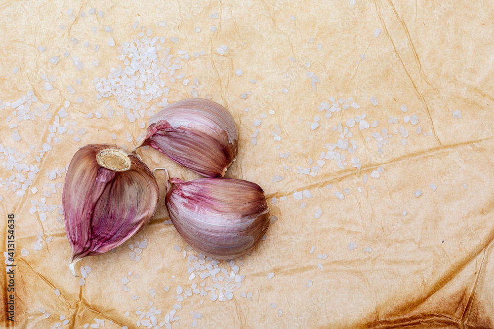 Group of red garlic cloves and salt grains. On a beautiful rustic ...
