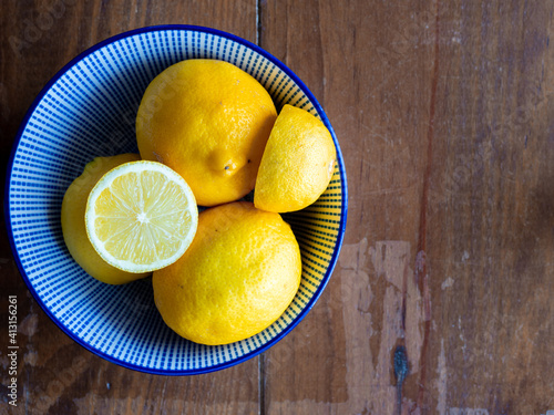 Top view of lemons in a bowl on wooden table with space