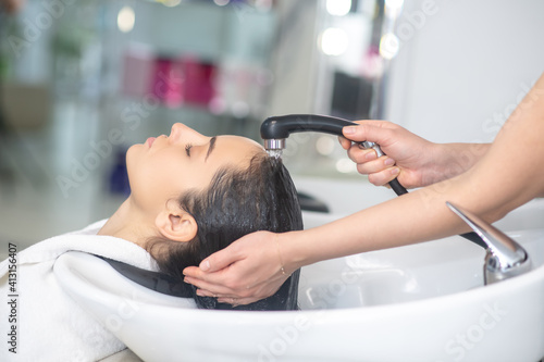 Woman looking relaxed while hair stylist washing her hair