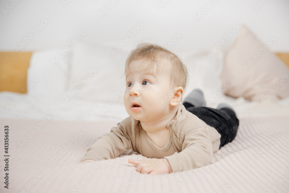 Surprised little baby man lies on bed and looks to side, place for text