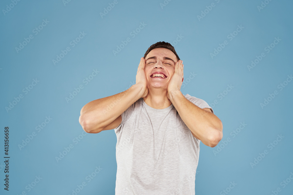 cheerful man in a white t-shirt gesturing with his hands emotions blue background cheerful man in a white t-shirt gesturing with his hands emotions blue background