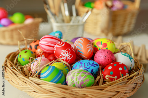 Group of easter eggs painted with handmade and bright color in basket and paintbrush tools blur in the background