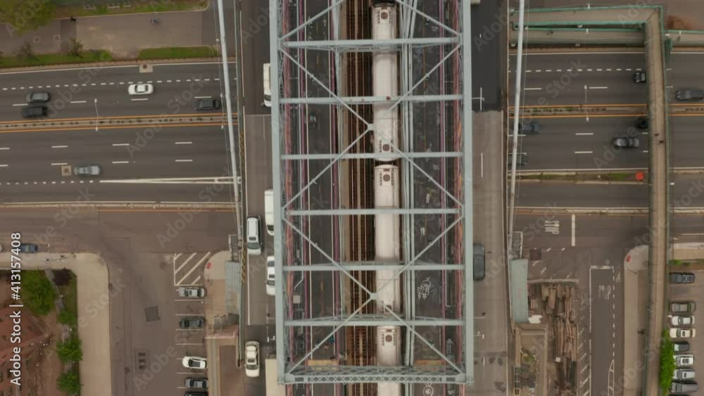 Top down overhead aerial view following a subway train driving on the Williamsburg Bridge and crossing busy multi lane highway in New York City Top down overhead aerial view following a subway train driving on the Williamsburg Bridge and crossing busy multi lane highway in New York City