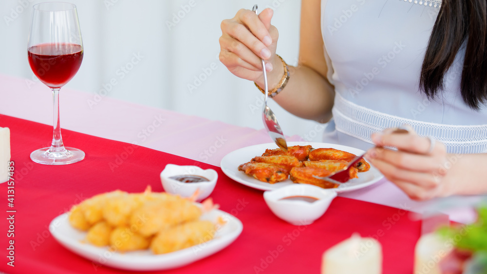 Woman eating chicken wings and glass of wine in food shop