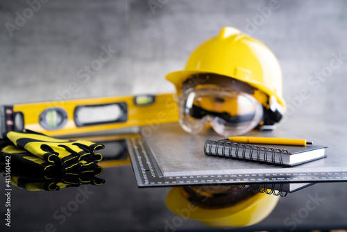 Contractor concept. Tool kit of the contractor: yellow hardhat, libella and tools on the gray background. © zolnierek