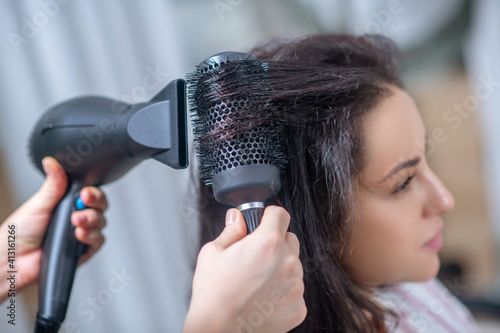 Dark-haired woman making hairstyling in a hair salon