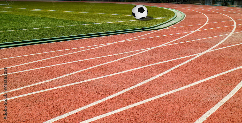 Obraz premium Soccer ball black and white classic with lines on green artificial grass at public outdoor football stadium with runing track field, sport,