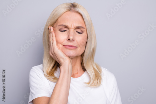 Photo of pensioner lady palm cheekbone suffer toothache closed eyes wear white t-shirt isolated grey color background
