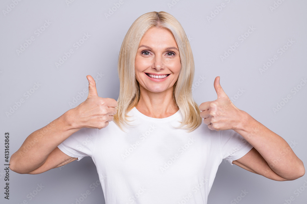 Photo portrait of elderly lady pointing two thumbs up isolated on grey colored background Photo portrait of elderly lady pointing two thumbs up isolated on grey colored background