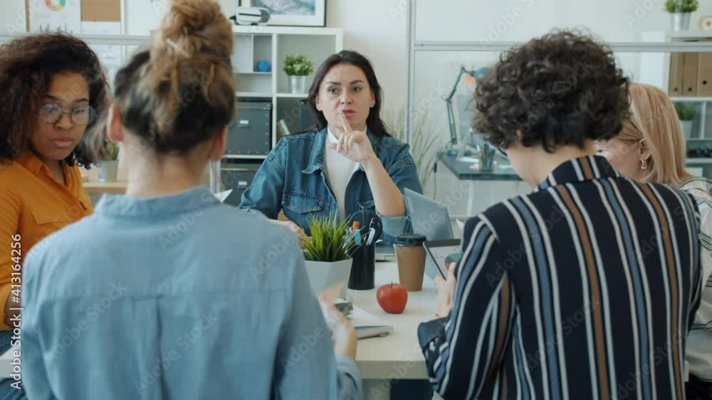 Ambitious women diverse group are discussing business talking and gesturing sitting at desk in workplace. Conversation and modern career for ladies concept. Ambitious women diverse group are discussing business talking and gesturing sitting at desk in workplace. Conversation and modern career for ladies concept.