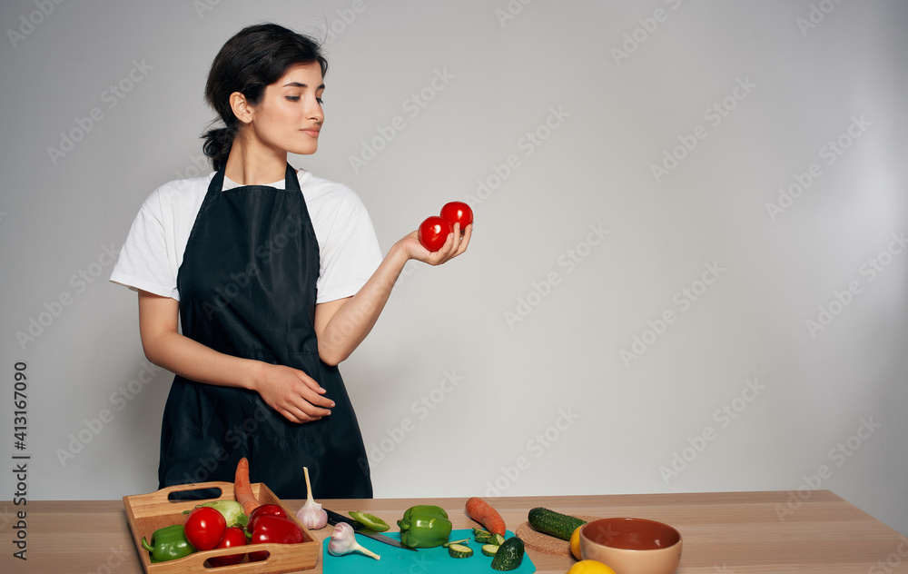 Woman chef in black apron slicing vegetables cooking food healthy food household Woman chef in black apron slicing vegetables cooking food healthy food household