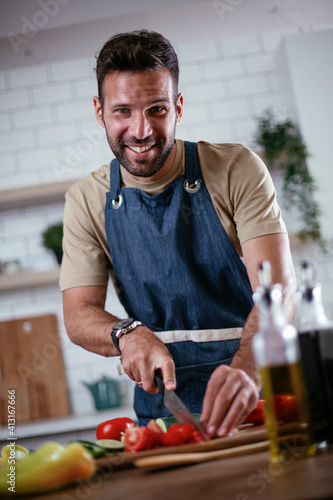 Portrait of handsome man cutting vegetables. Young man preparing salad.