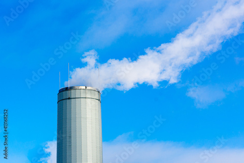 One Industrial smoke pipe from chimney on blue cloudy sky.