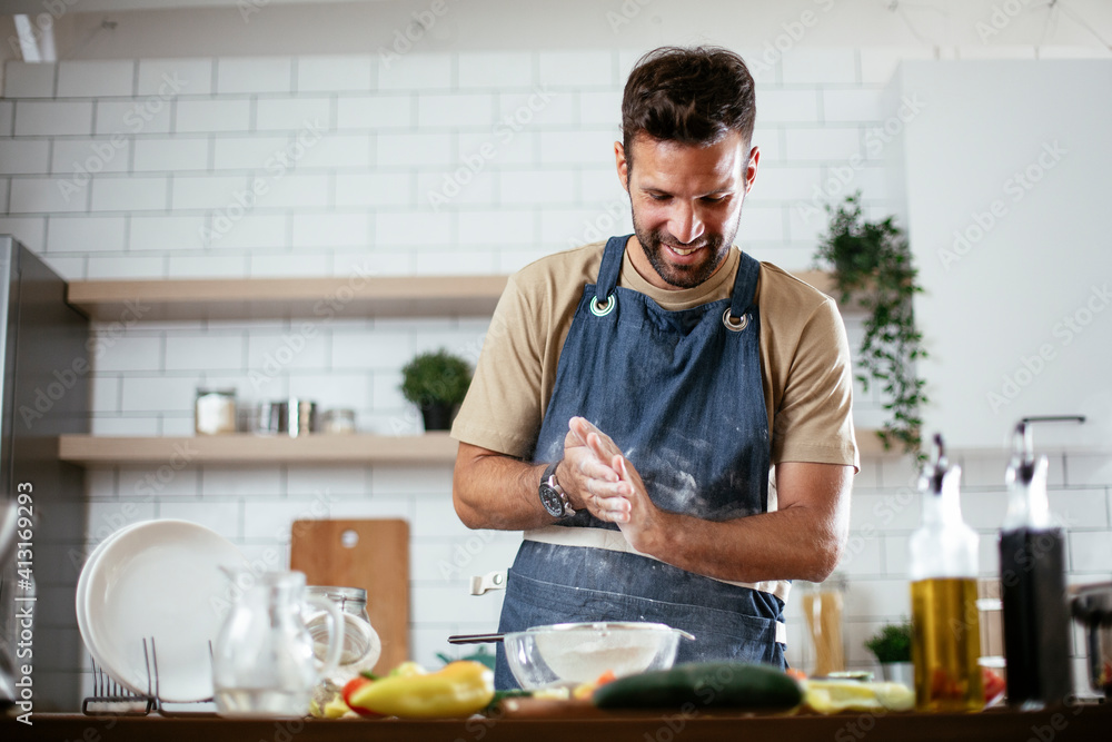 Happy man baking in the kitchen. Man making delicious food at home.. Happy man baking in the kitchen. Man making delicious food at home..