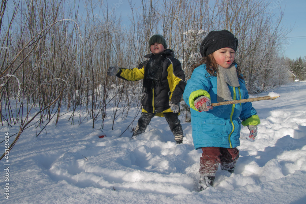 Children play in the winter forest on a clear sunny day in winter
