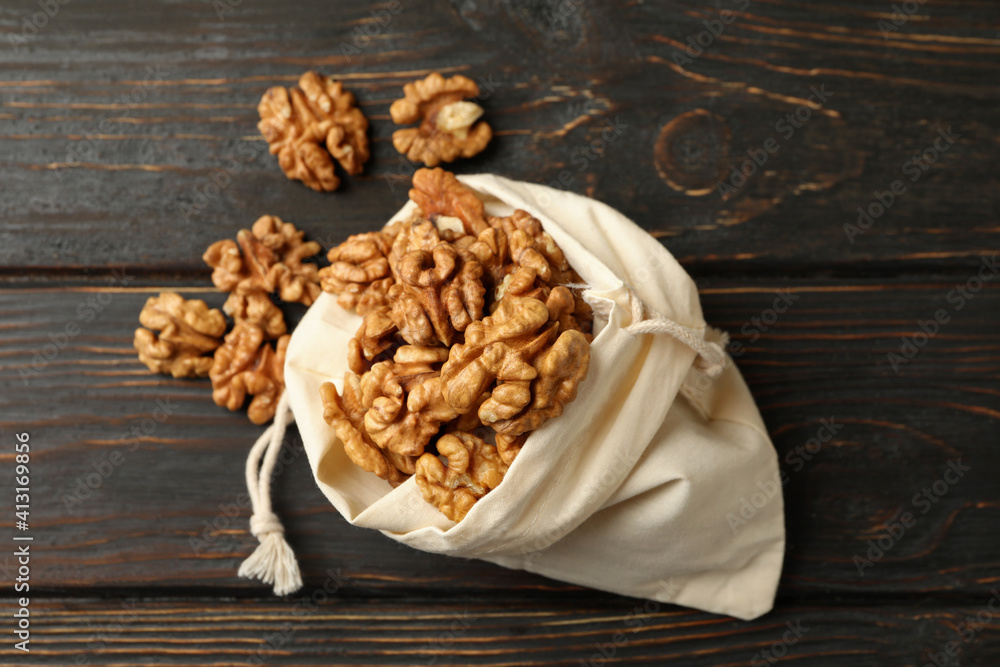 Fototapeta premium Cotton bag with tasty walnuts on wooden background