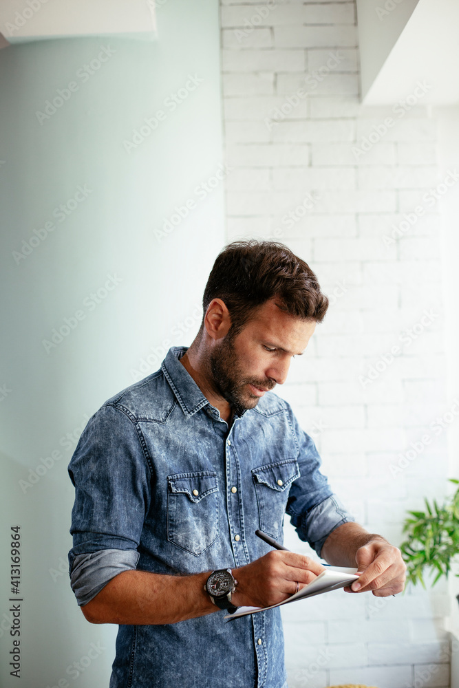 Handsome businessman sitting on a desk, writing notes. Businessman making businessplan.
